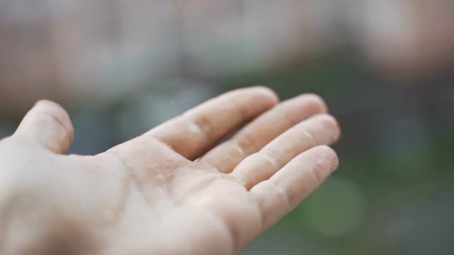 Drops of rain fall into the hand male.