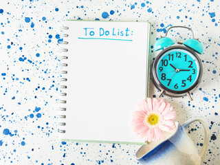 Writing To do list in the morning concept with flower and alarm clock.