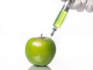 Injection into an apple, GMO concept, pesticides, poisons. White background.