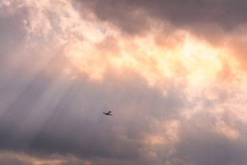 Airplane flying through beams of sunlight
