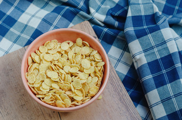 Cornflakes in a pink bowl, on a wooden table. copy space