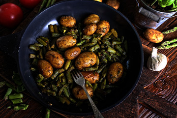 Potatoes fried with asparagus in a pan with spices