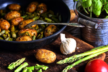 Potatoes fried with asparagus in a pan with spices and tomatoes