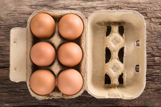 Braune Eier in Eierschachtel oder Eierkarton, fotografiert von oben auf Holz (Selektiver Fokus, Fokus auf die Oberseite der Eier)