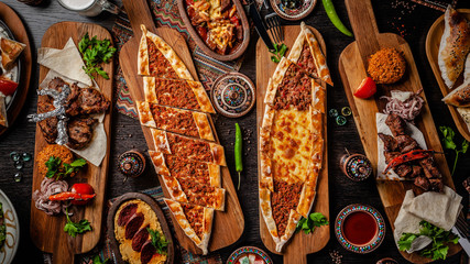 Traditional Turkish cuisine. Pizza, pita, pidesi, sucuk, hummus, kebab, bulgar. Many dishes on the table. Serving dishes in restaurant. Background image. Top view, flat lay