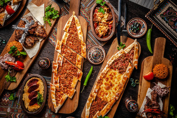 Traditional Turkish cuisine. Pizza, pita, pidesi, sucuk, hummus, kebab, bulgar. Many dishes on the table. Serving dishes in restaurant. Background image. Top view, flat lay - obrazy, fototapety, plakaty