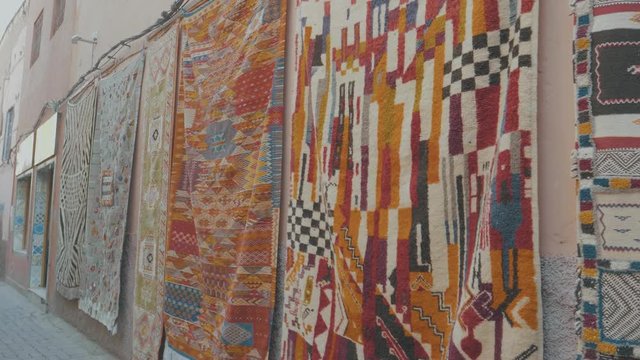 Beautiful colorful patterned rugs hanging from the walls of buildings in Morocco on a sunny day