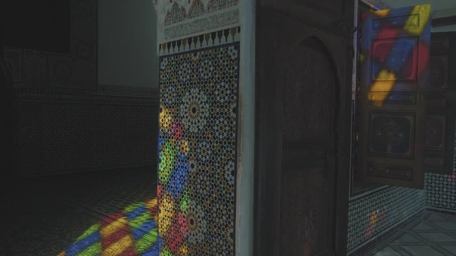 Panning around a room in a tradition building in Morocco reflecting colorful lights from stained glass windows with decorated patterned mosaic walls