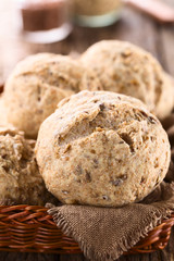 Fresh homemade wholegrain bread rolls with linseeds and sunflower seeds in basket (Selective Focus, Focus on the front of the first bread roll)