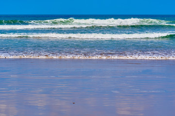 Ocean waves on the dark sand beach.