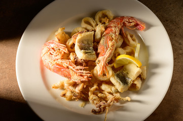 Grilled Calamari (Squid) and shrimps with lemon and parsley on white plate on a plate in restaurant ready to be served