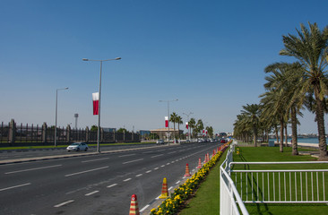 Fototapeta na wymiar Road with alley with palm trees in the city of Doha city, Qatar