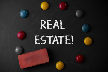 Word writing text Real Estate. Business photo showcasing owning property consisting of empty land or buildings Round Flat shape stones with one eraser stick to old chalk black board