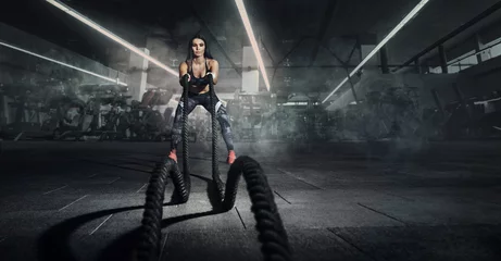  Sport backgrounds. Powerful attractive muscular woman fitness trainer do battle workout with ropes at the gym. © vitaliy_melnik