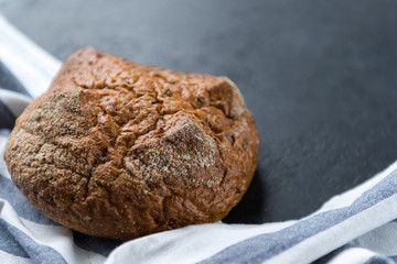 loaf of rye bread with a towel on a dark background