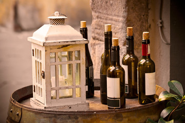 Red wine bottles uncorked over a wooden barrel with lantern