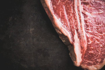 Raw fresh marble T-bone meat on the rustic background. Selective focus. Shallow depth of field.