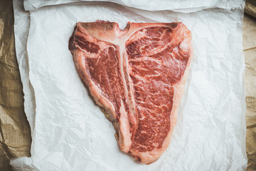 Raw fresh marble T-bone meat on the rustic background. Selective focus. Shallow depth of field.