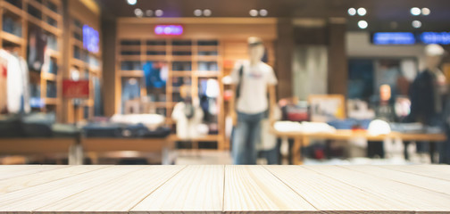 Empty wood table top with abstract blur clothing store in modern shopping mall defocused background