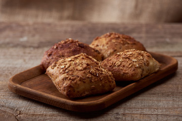 fresh baked buns with grains on wooden board on table