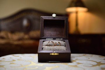 Wedding rings lie a wooden box and a cloth of burlap. Wedding rings and box in rustic style. Close-up