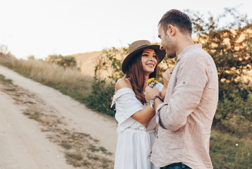 Outdoor shot of young couple in love walking on pathway through grass field. Man and woman walking along tall grass field. 