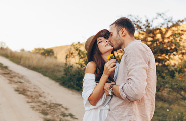 Outdoor shot of young couple in love walking on pathway through grass field. Man and woman walking along tall grass field. Valentine's day