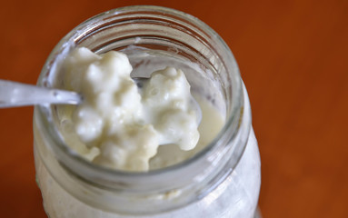 A teaspoon stirs the kefir and raises some granules in a close-up shot