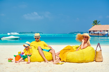 Family on beach, young couple in yellow with three year old boy. Summer vacation at Maldives.