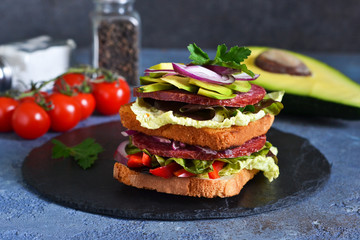 Crispy sandwich with salami, salad and vegetables on the kitchen table. View from above.