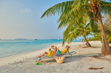 Plakat Family on beach, young couple in yellow with three year old boy. Summer vacation at Maldives.