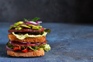 Crispy sandwich with salami, salad and vegetables on the kitchen table. View from above.