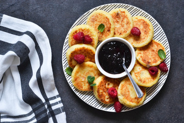 Breakfast time. Cheese cakes with raspberry sauce for breakfast on the kitchen table. View from above.