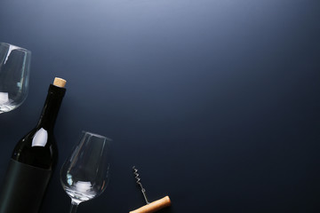 Vintage bottle of red wine with blank matte black label, corkscrew on graphite gradient table background. Expensive bottle of cabernet sauvignon concept. Copy space, top view, flat lay.