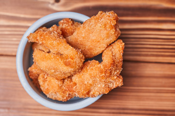Chicken strips in a clay pot on a wooden table.