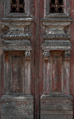 Close-up of two old wooden doors with red and brown peeling paint