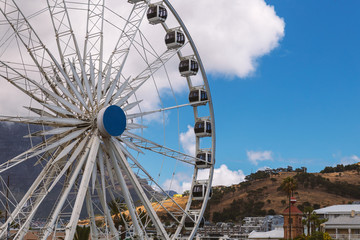 Fototapeta premium Ferris wheel and Table Mountain view at Waterfront in Cape Town