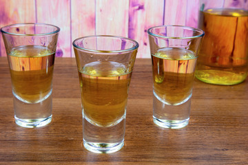 Three glasses of honey liqueur on a wooden table
