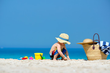 Two year old toddler boy playing with beach toys on beach