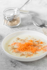 Semolina porridge with carrots and walnuts in a white plate on a light background