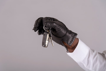 England, UK. May 2019. Man's hand wearing a black leather glove holding ignition keys,