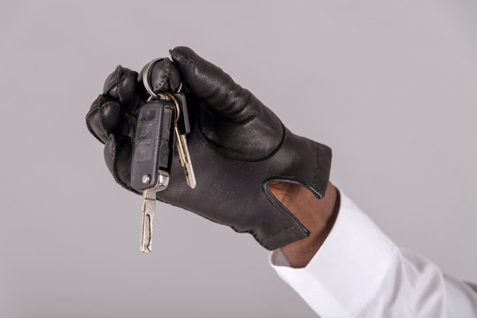 England, UK. May 2019. Man's hand wearing a black leather glove holding ignition keys,