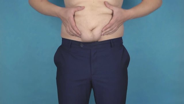 A young man rubs his fat folds on a thick anti-cellulite stomach, the concept of a wrong lifestyle and nutrition, the problem, slow motion, healthcare
