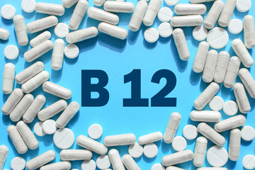 Vitamin B12 text in white capsules frame on blue background. Pill with cobalamin. Dietary supplements and medication