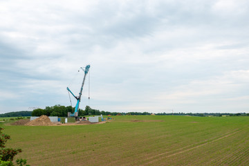 Fototapeta na wymiar in the middle of a field, a wind turbine is erected with the help of a large crane
