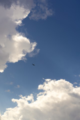 Beautiful blue sky and clouds. Creative vintage background. Very small plane on a background of clouds.