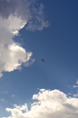 Beautiful blue sky and clouds. Creative vintage background. Very small plane on a background of clouds.