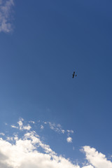 Beautiful blue sky and clouds. Creative vintage background. Very small plane on a background of clouds.