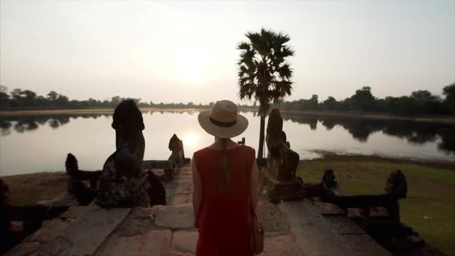 Following woman walking to enjoy sunrise at the bank of Srah Srang, a baray or reservoir dug in the mid-10th century by khmer civilization. Angkor Wat, Cambodia