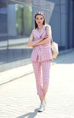 Obraz premium high fashion outdoor Portrait of a young woman. Pantsuit, pink color, long hair, sunglasses